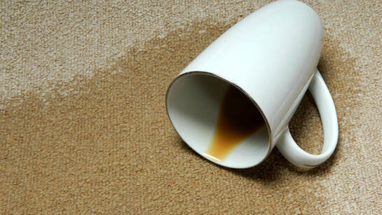 Photo of coffee cup on carpet spilling out coffee and staining carpet
